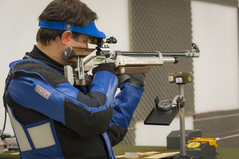 Foto de atleta apontando uma arma para executar o tiro