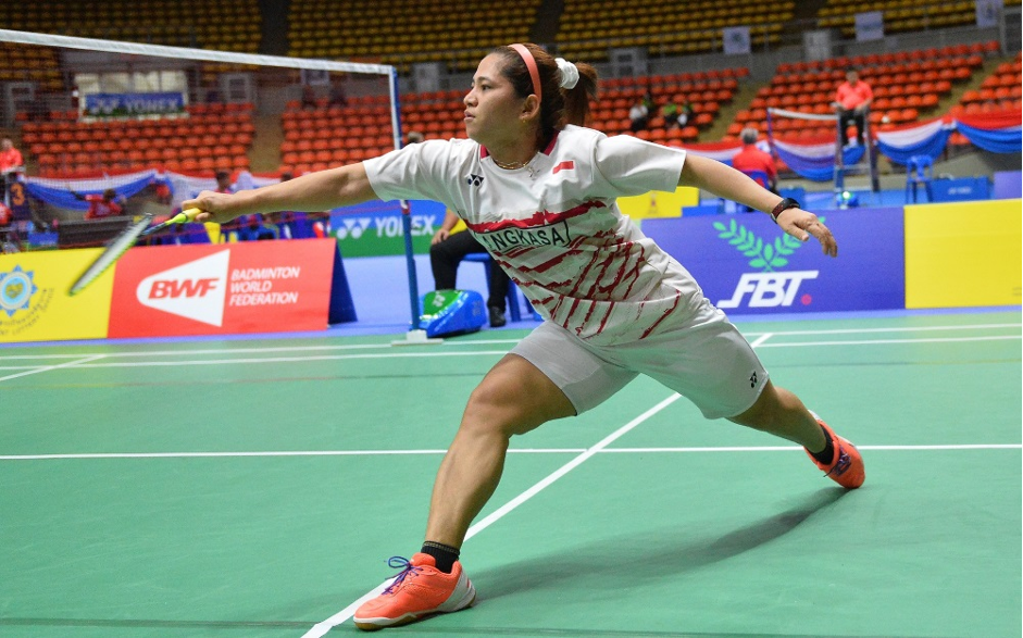 Foto de Leani jogando uma partida. Tem cabelo castanho e está vestida com um uniforme branco, meias pretas e tênis laranja e branco.