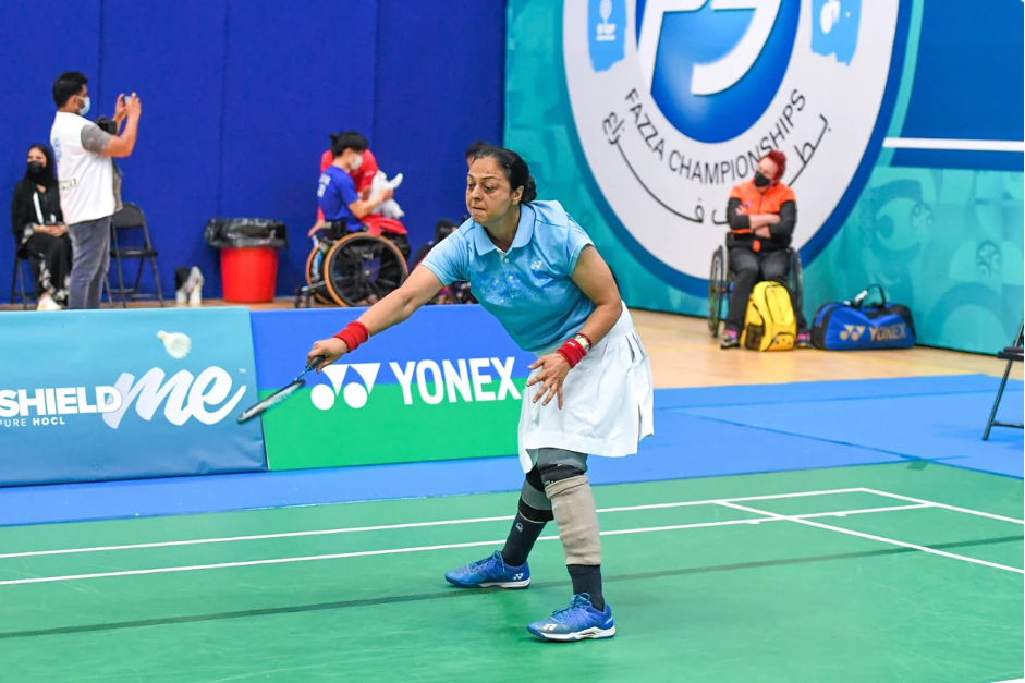 Foto de Parul jogando uma partida. Tem cabelos pretos e está vestida com uma camisa polo azul, saia branca, munhequeiras vermelhas e tênis azul. Usa faixas pretas nas suas pernas.