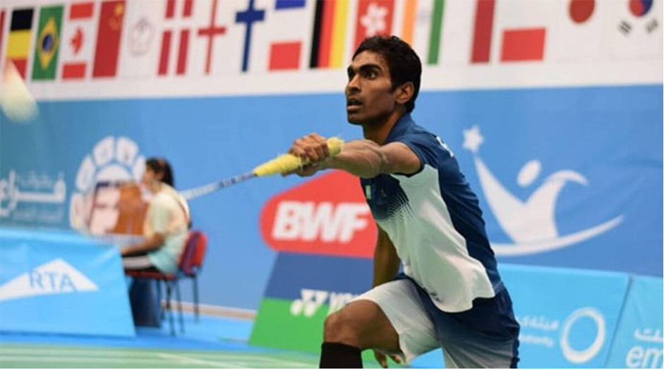 Foto de Pramod jogando uma partida. Tem cabelo escuro e pele escura e está vestido com um uniforme azul e branco.