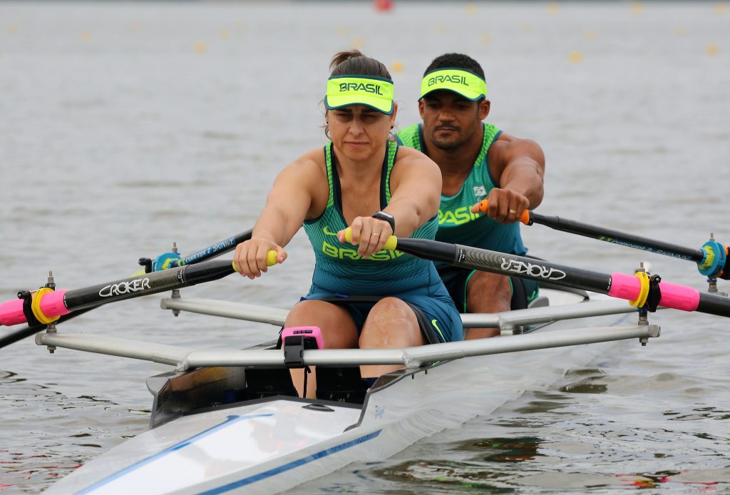 Josiane está remando sobre a água junto a Michel Gomes na canoa
